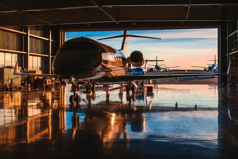 Business jet in hangar with sunset reflections, symbolizing aviation sector and legal services for transportation and logistics.